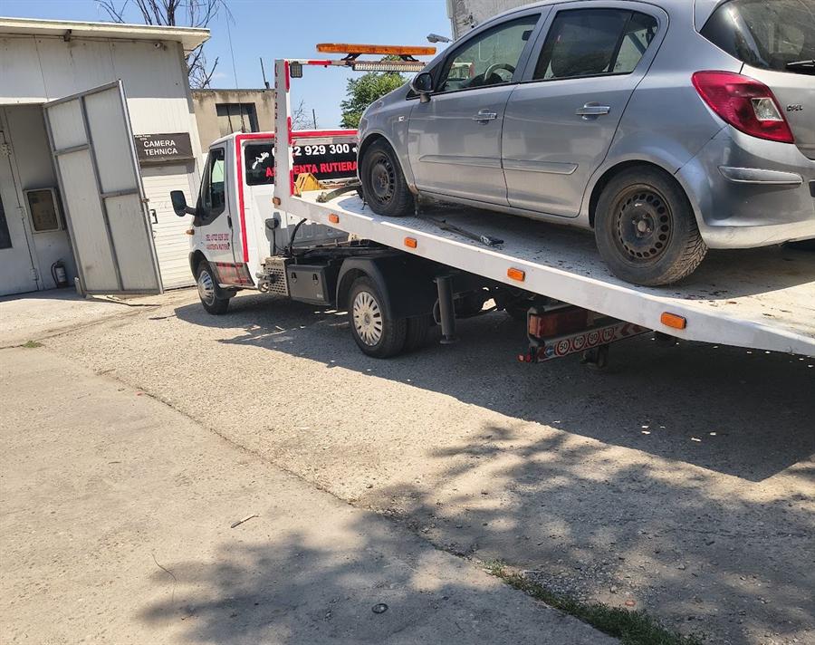 Autoturism mic pe platformă, într-o curte de service.