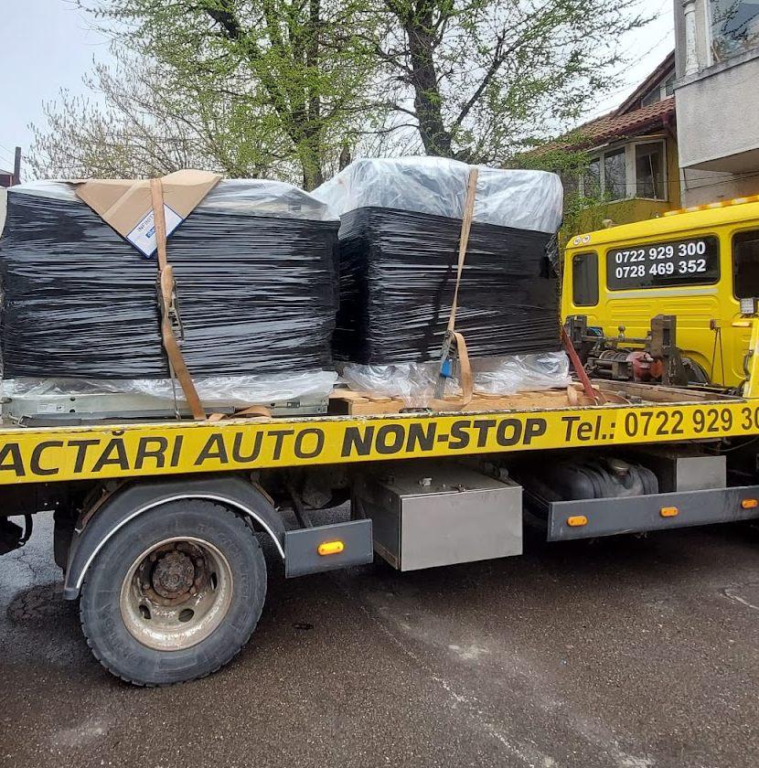 Camion cu platformă încărcat cu palete de marfă industrială înfoliată.